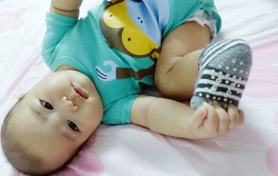 Low section of baby lying on bed