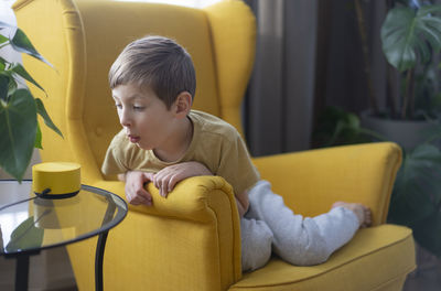 Cute boy using laptop while sitting on sofa at home