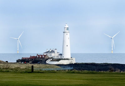 Traditional windmill by sea against sky