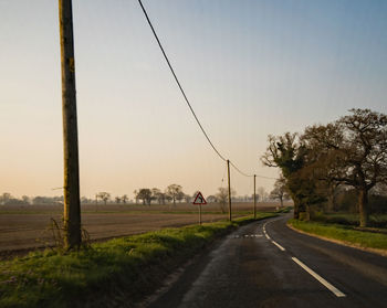 Road by trees against clear sky