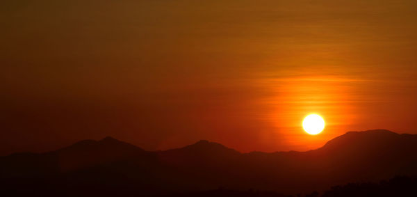 Scenic view of silhouette mountains against romantic sky at sunset