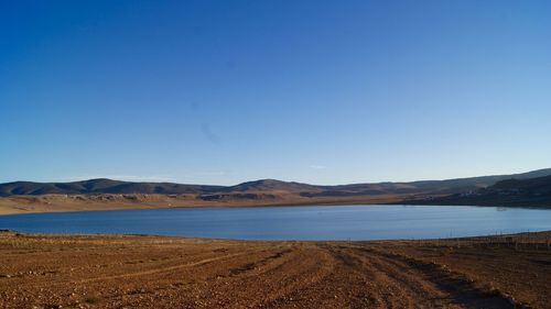 Scenic view of calm lake against clear blue sky