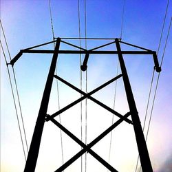 Low angle view of electricity pylon against blue sky