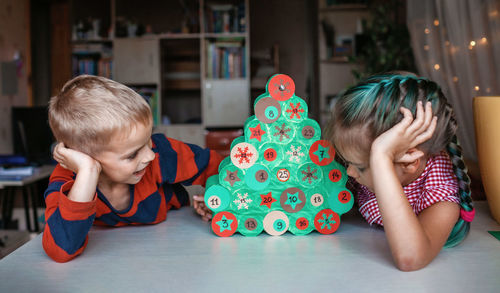 Cute kids looking at christmas tree at home