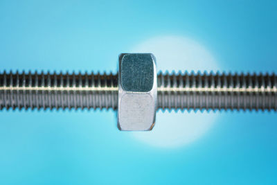 Close-up of  a steel nut against blue background