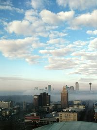 View of cityscape against cloudy sky