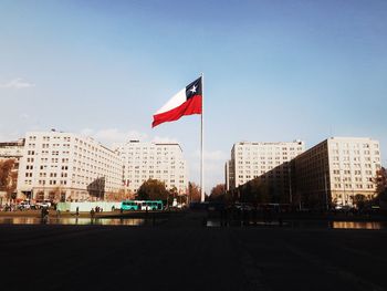 Flags on street by buildings against sky in city