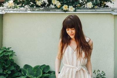 Portrait of a smiling young woman standing against plants