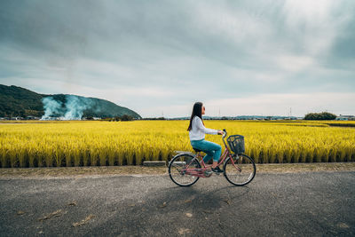 Rear view of man cycling on field