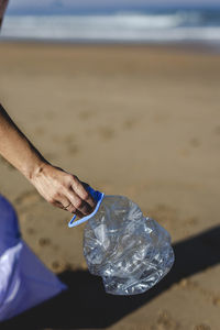 Cropped hand of person holding bottle at beach