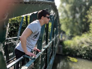 Side view of young man on footbridge over canal