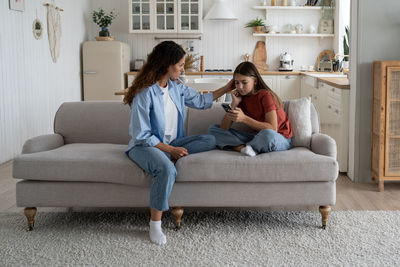 Young woman using phone while sitting on sofa at home