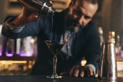 Male bartender preparing cocktail at bar counter