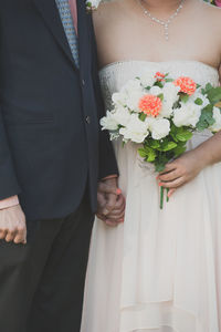 Midsection of couple holding bouquet