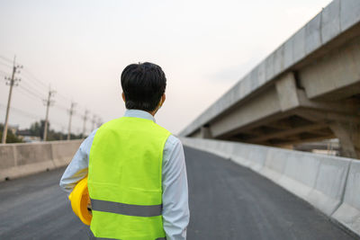 Rear view of man standing on bridge against sky