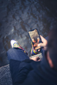 Low section of man holding mobile phone