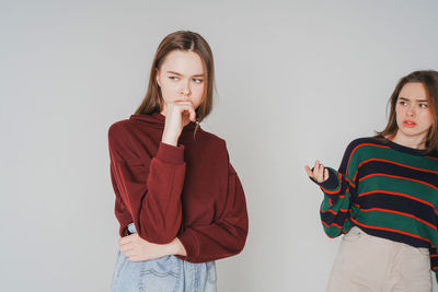 Young lesbian couple standing against gray background