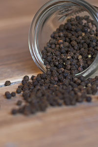 Close-up of black peppercorn spilling from jar on table
