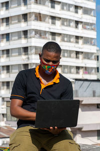 Young man using laptop in city