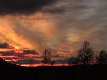 Silhouette landscape against dramatic sky during sunset