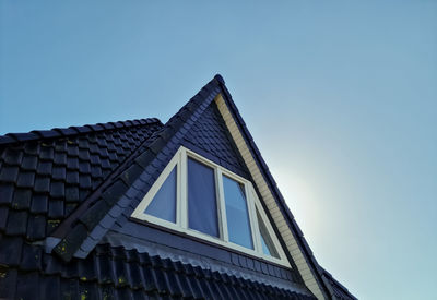 Open roof window in velux style with black roof tiles