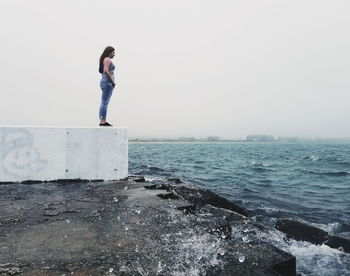 Woman standing by sea against sky