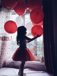 Young woman with balloons in window