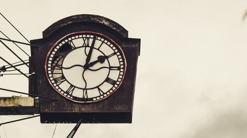 Low angle view of clock against sky