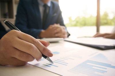 Cropped image of businesswoman writing on graph at desk in office