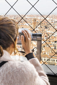 Woman looking city through binoculars