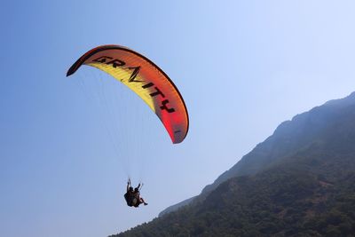 Low angle view of person paragliding against sky