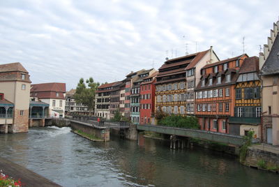 Buildings by river against sky in city