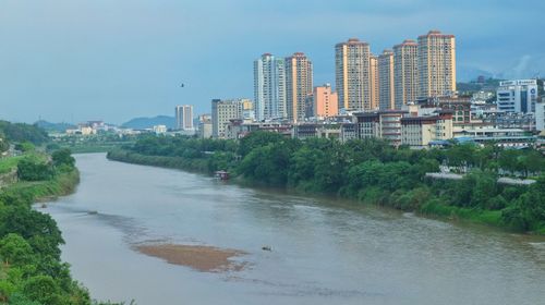 River amidst buildings in city against sky