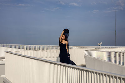 Side view of woman standing by railing against sky