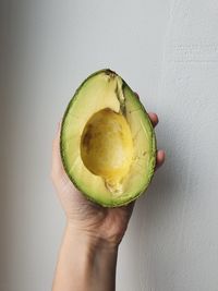 Close-up of hand holding fruit against white wall