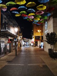 Illuminated street amidst buildings in city at night