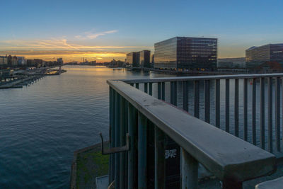 River by buildings against sky during sunset