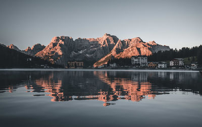 Reflection of buildings in lake against clear sky