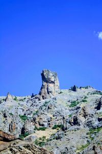 Rock formations on landscape against clear blue sky