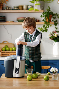 Cute schoolboy makes fresh apple juice for breakfast. vitamins and healthy nutrition for schoolers