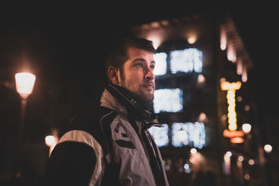 Portrait of young man looking away at night