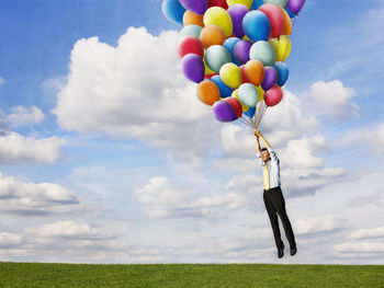 Low angle view of balloons on field against sky