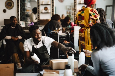 Male hairdresser discussing with female coworker in barber shop