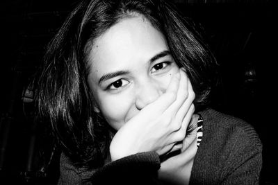 Portrait of young woman against black background