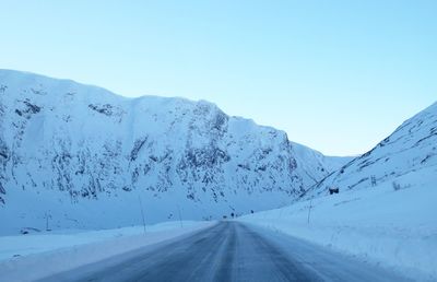 Scenic view of road against clear sky during winter