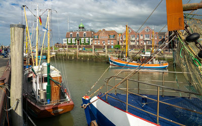 Boats moored in canal by harbor against sky