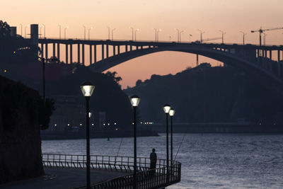 Bridge over sea against sky during sunset