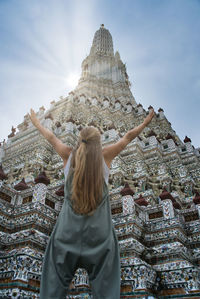 Rear view of woman standing outside temple against building