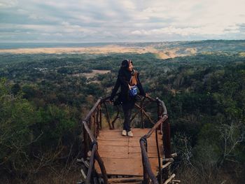 Woman standing on landscape against cloudy sky