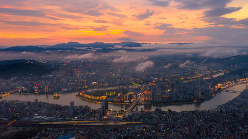 High angle view of illuminated city against sky at sunset